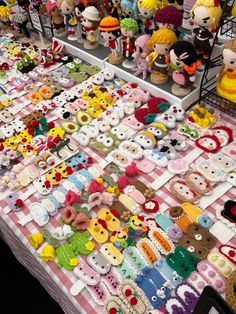 there are many stuffed animals on display at the table with other toys and dolls behind them