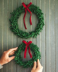 two hands are making a christmas wreath out of yarn