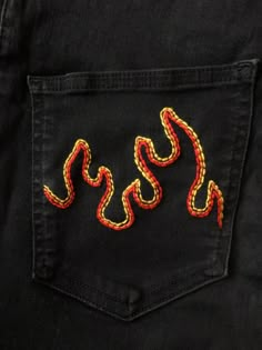 the back pocket of a pair of black jeans with red and yellow snake embroidered on it