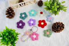 several crocheted flowers and pine cones are arranged on a white furnishing