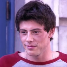 a close up of a person wearing a red and white shirt with a blue door in the background