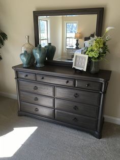 a dresser with a mirror and vases on it in a room that has carpeted flooring