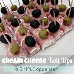 small desserts are arranged on sticks with black and green apples in the middle, sitting on a white tablecloth