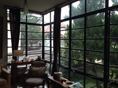 a living room filled with furniture and lots of window panes that look out onto the trees