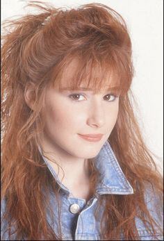 a woman with long red hair wearing a denim shirt