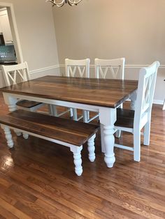 a dining room table and bench with white chairs