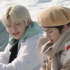 two young men sitting next to each other in the snow