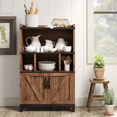 a wooden cabinet filled with dishes next to a potted plant