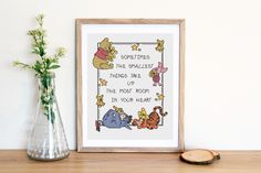 a cross stitch winnie the pooh birth chart is displayed next to a vase with flowers