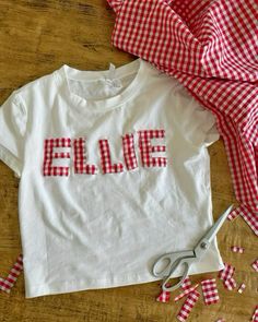 a red and white gingham shirt with the word ellene on it next to scissors