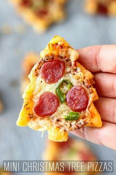 a slice of pizza with pepperoni, green peppers and cheese is held up to the camera