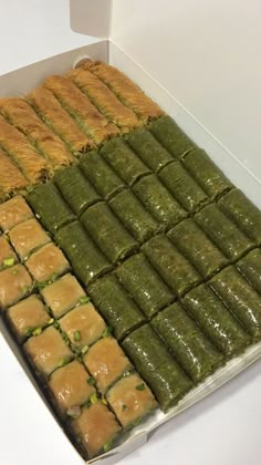 an open box filled with green desserts on top of a white counter next to another box