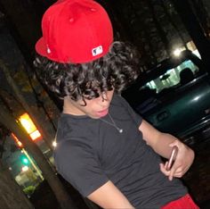 a young man wearing a red hat looking at his cell phone