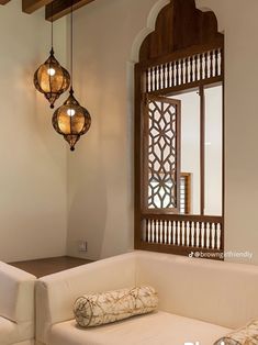 a white couch sitting under a window next to a lamp on a wooden ceiling above it