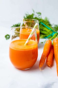 carrots and juice are sitting next to each other on a table with green stems