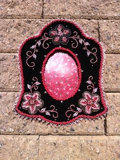 a black and pink object is laying on the ground next to a brick wall,