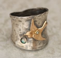 "This wide band ring was inspired by nature and also works great as a thumb ring! The wide sterling silver band has a gently hammered texture and is oxidized and then hand buffed to show highlights. Accenting the sterling silver ring is a 14kt gold filled bird or swallow. The center of the bird is embellished with a tiny real pearl! Below the bird is a place for your choice of a Czech cabochon. Please choose the color you would like from the personalize option. The is set in a 925 sterling silve Silver Bird Ring, Bird Watcher Gifts, Birthstone Ring Mothers, Bird Ring, Bird Rings, Hammered Silver Ring, Silver Rings With Stones, Wide Band Ring, Bird Gifts