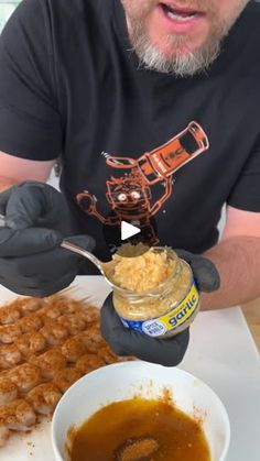 a man in black shirt and gloves eating food from a white bowl with sauce on it