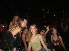 group of young women posing for the camera in front of a crowd at night time