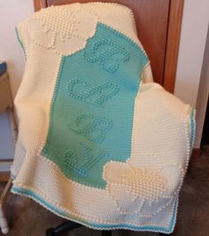 a crocheted baby blanket sitting on top of a chair next to a wooden door