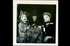 an old photo of three people dressed up as cats and dogs at a dinner table