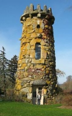 an old stone tower with graffiti on it's side in the middle of a field