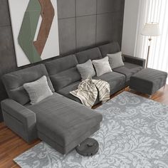 a living room with grey couches and rugs on the hardwood floor, along with a large painting