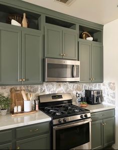 a stove top oven sitting inside of a kitchen next to green cabinets and counter tops