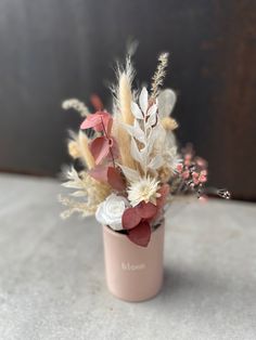 a pink vase with flowers and feathers in it