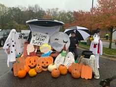 people dressed up in costumes and holding umbrellas near a car with pumpkins on it