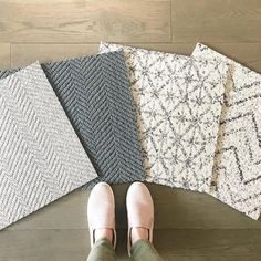 a person standing on the floor with four different rugs in front of their feet