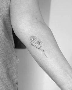 a black and white photo of a person's arm with a flower tattoo on it