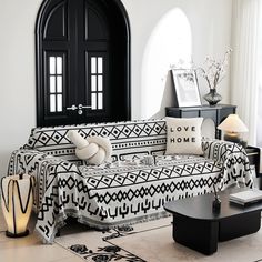 a black and white living room with an ornate couch, coffee table, lamps and pictures on the wall