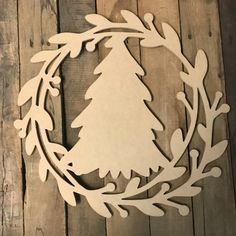 a wooden cutout of a christmas tree in a wreath on a wood background with planks