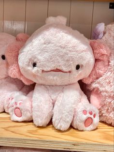 three pink stuffed animals sitting on top of a wooden shelf next to eachother