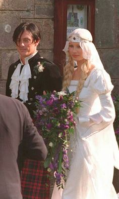 a man and woman in wedding attire standing next to each other