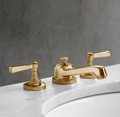 two golden faucets sitting on top of a white sink