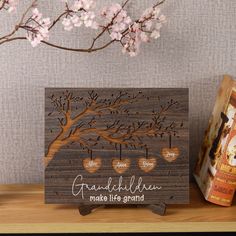 a wooden family tree with hearts hanging from it's branches on a shelf next to a book