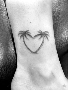 a heart shaped tattoo with two palm trees on the side of the foot, and an open caption below