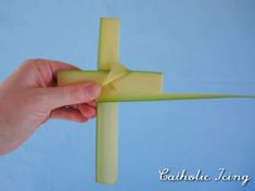 a hand holding a piece of yellow paper in front of a blue background with the word catholic jesus on it