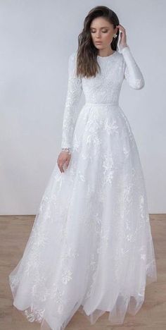 a woman wearing a white wedding dress with long sleeves