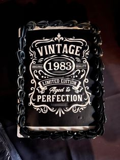 a black cake with white icing and an old fashioned label on the side that says vintage 1989