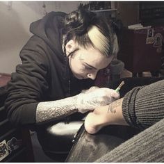 a woman with tattoos is getting her nails done