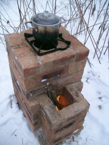 an old brick stove with a pot on top sitting in the middle of some snow