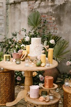 a table topped with a white cake next to lots of flowers and candles on top of it