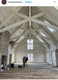 two people standing in the middle of a large room with high ceilings and exposed beams