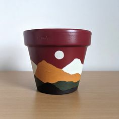 a painted pot sitting on top of a wooden table