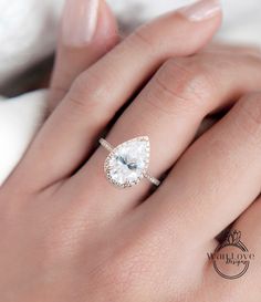 a woman's hand with a ring on her finger and a pear shaped diamond in the middle