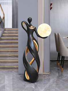 a large black and gold vase sitting on top of a table next to a stair case