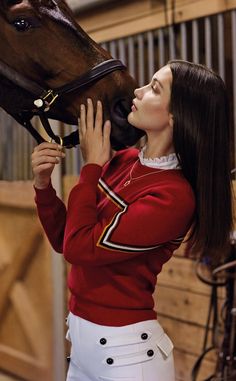 a woman in a red shirt is kissing a brown horse